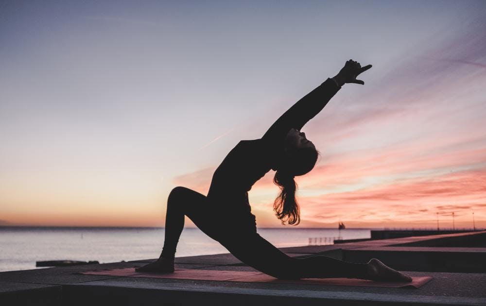 Women doing yoga in front of sunset