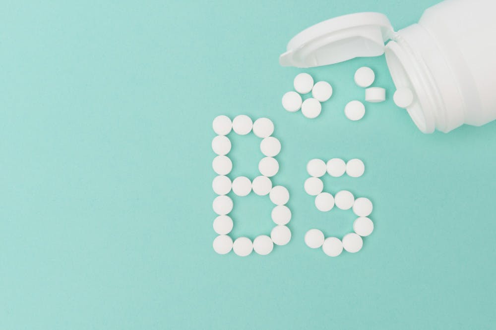 Pill bottle against a turquoise blue background with pills coming out of the bottle forming the shape 'B5'.