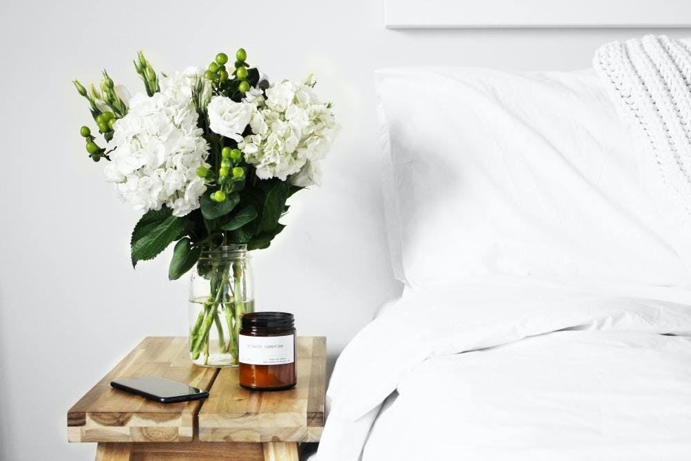 Bedroom and bed with flowers on the night stand.