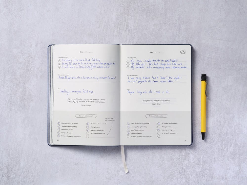 Braincare Journal open on journalling page with pen