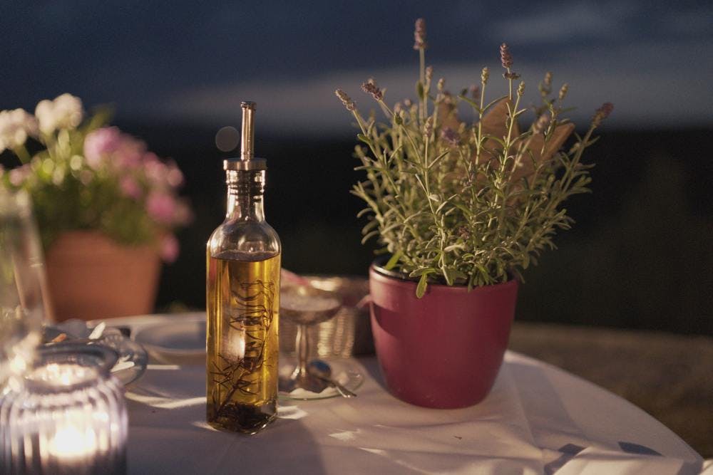 olive oil on a table next to herbs