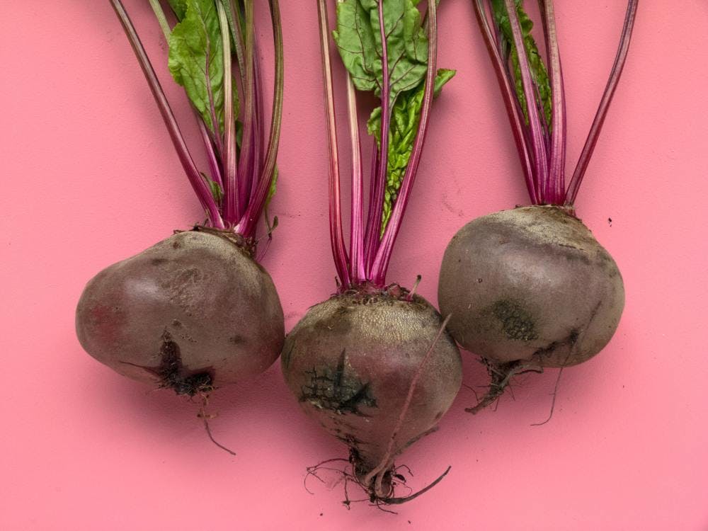 Three beets against a pink background