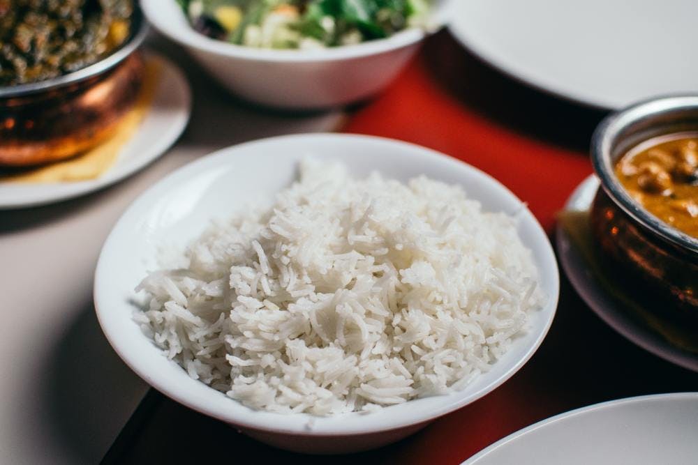 White rice on a table surrounded by other dishes