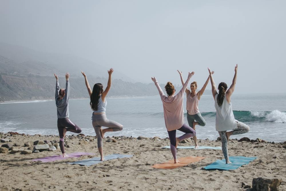 Several women doing yoga on the beach